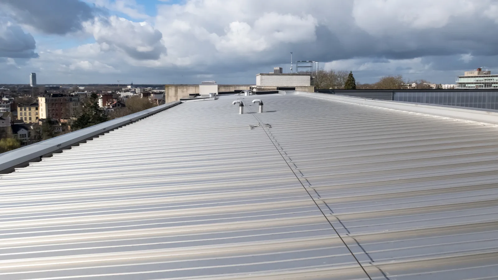 Ribbed metal panel roof running toward a building parapet.